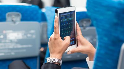 Businessman using tablet phone on airplane