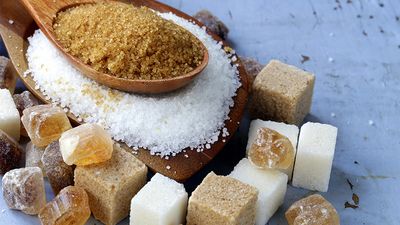 Various types of sugar. Organic compound. Glucose. Refined sugar, raw sugar, brown sugar, sugar cubes spoon wood