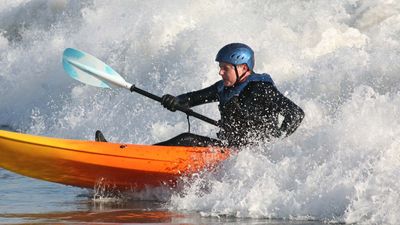 An open-water kayaker paddling through ocean waves.