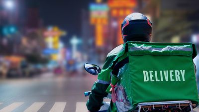 Delivery driver on motorcycle or moped driving in the city. Delivering online food orders. Gig economy, Grubhub, Uber Eats, Doordash, restaurant