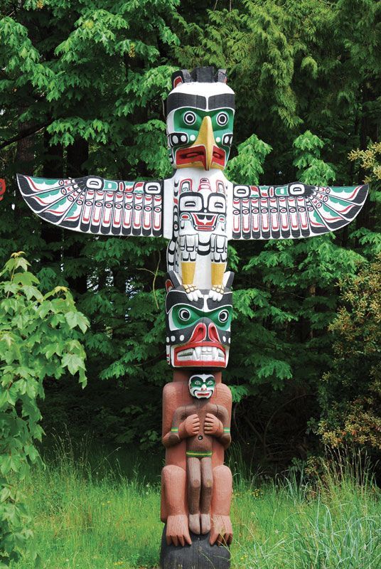 A totem pole stands among trees.